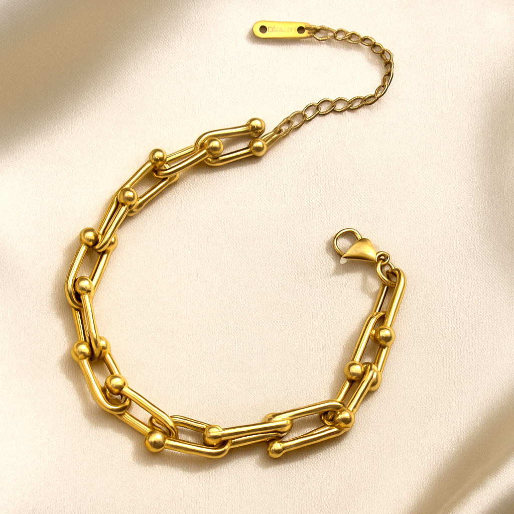 Orbit-inspired gold chain bracelet with sphere-accented links on satin background