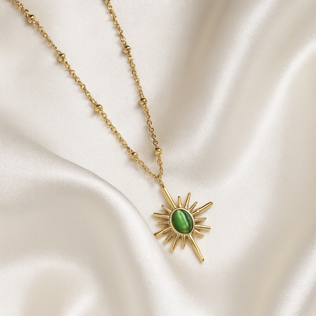 18 carat gold plated sunburst necklace with green stone pendant on satin background