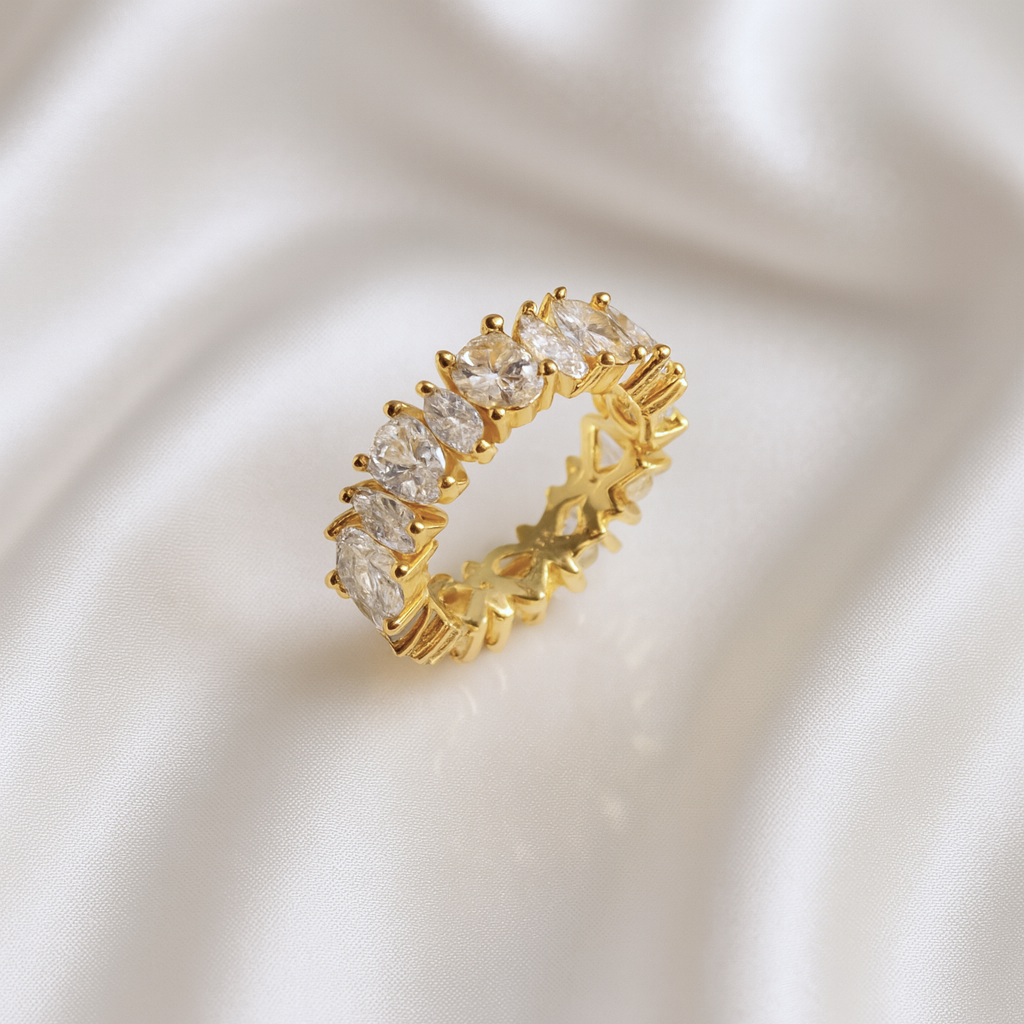 Gold eternity band with marquise-cut zirconia stones placed on ivory satin fabric