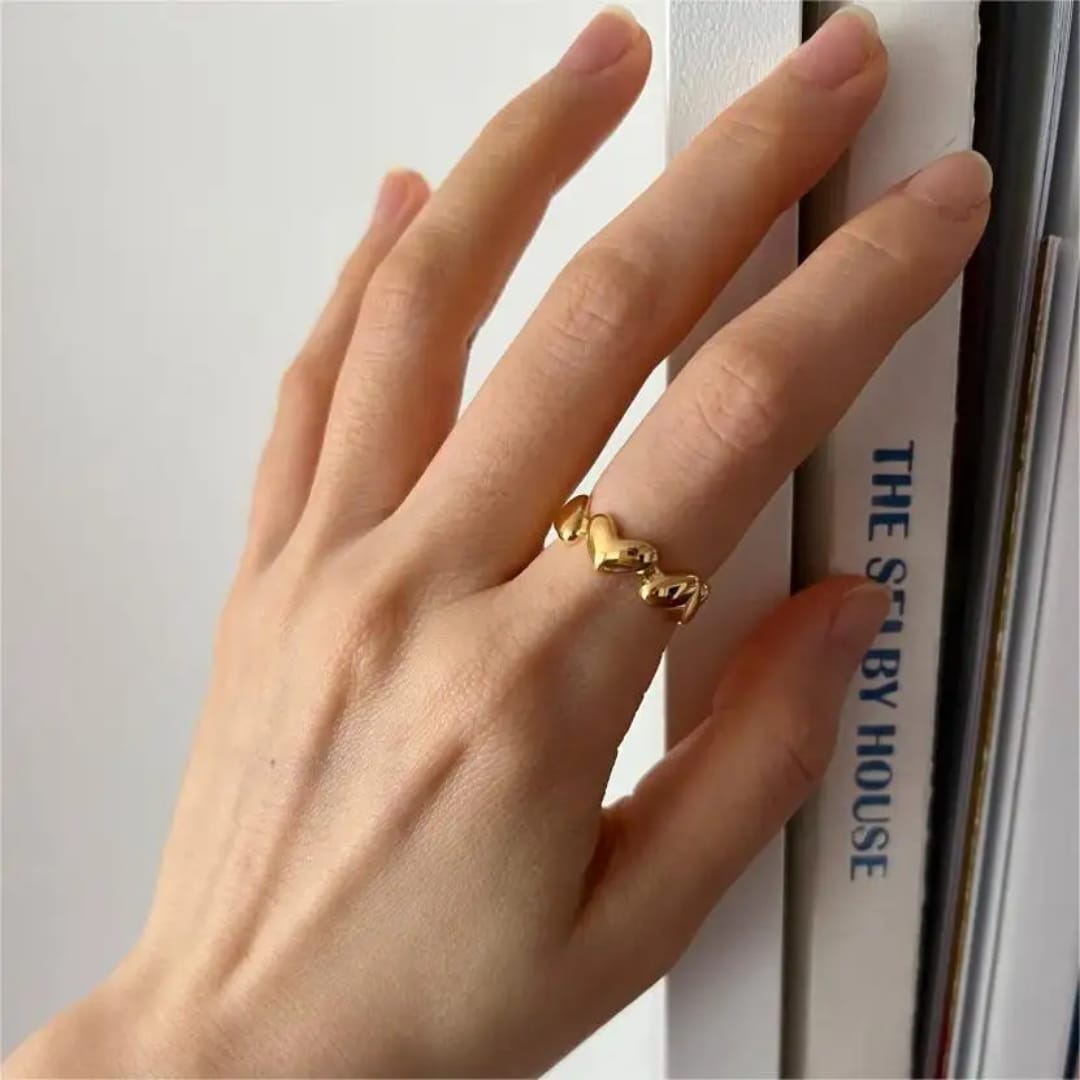 Eternal Hearts 18 Carat Gold Adjustable Ring A gold ring made of small heart links resting on a white ceramic cup