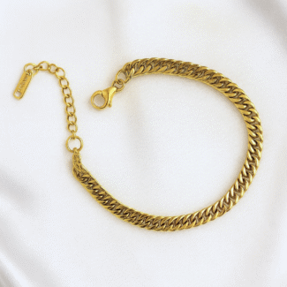 Gold plated Cuban chain bracelet on ivory satin background
