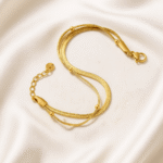 Triple-layered gold bracelet with bead accents and lobster clasp, displayed on satin fabric