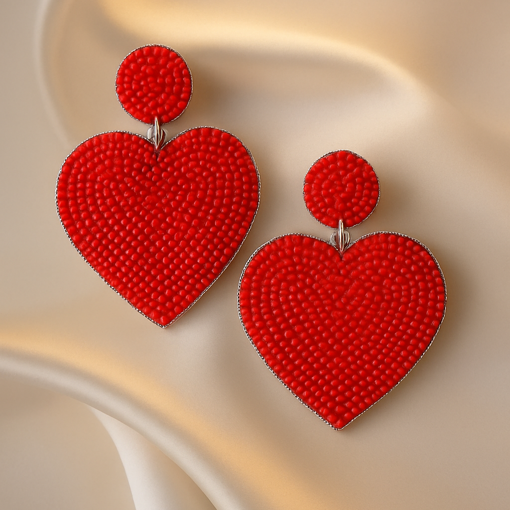 Handcrafted red beaded heart drop earrings on champagne satin background — statement festive jewellery by Masaira