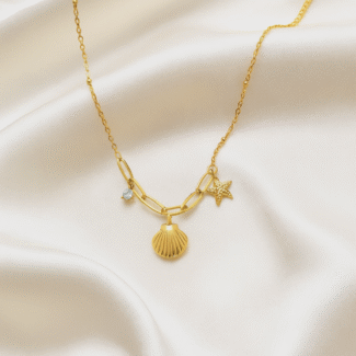 18 carat gold plated necklace with seashell, starfish, and crystal charms on satin background