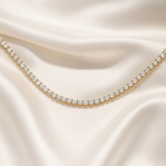 Gold-plated tennis necklace with simulated diamonds on ivory satin background