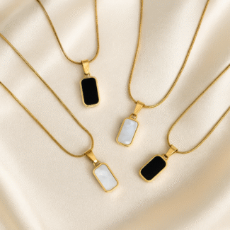 Reversible gold pendant necklace with black and white enamel on satin background