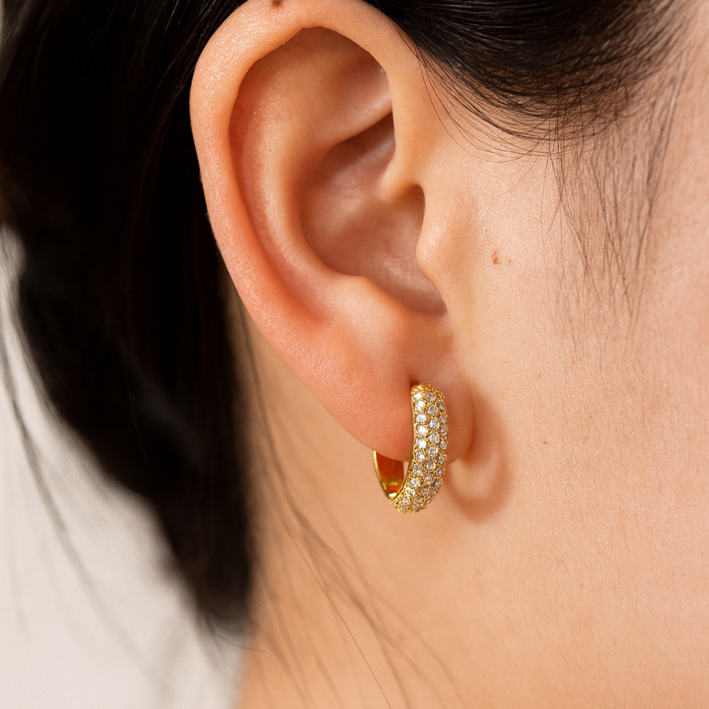 Create a hyper-realistic, high-resolution, high-definition product image using the attached photograph of the jewelry piece exactly as it is — without altering the design, shape, size, or any intricate details. Replace the current background with a luxurious ivory white satin silk fabric that features soft folds, natural highlights, and realistic shadows to enhance the premium aesthetic. The jewelry should appear naturally placed or subtly floating on the satin surface, as seen in a professional studio shoot. Make sure the yellow colour of the gold is not very cheap yellow colour but is very subtle and luxurious yellow colour. Include a soft, natural shadow or subtle reflection beneath the product to add depth and realism. Ensure the final image is in a clean 1:1 square aspect ratio — ideal for high-end e-commerce or website display. looking for very very clear image