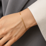 Minimal 18 carat gold plated open bracelet worn on wrist, styled against grey and white fabric