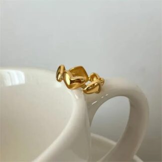 18 carat gold plated ring with interlinked heart design on a white ceramic mug