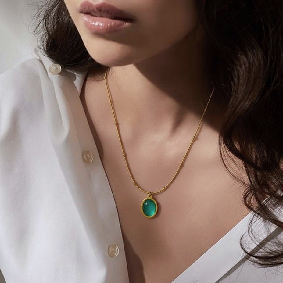 Emerald Aura Necklace | 18 Carat Gold Plated Green Stone Pendant | Anti-Tarnish & Hypoallergenic Emerald Aura Necklace with green oval stone pendant on 18 carat gold plated chain, worn with a white blouse, anti-tarnish and hypoallergenic