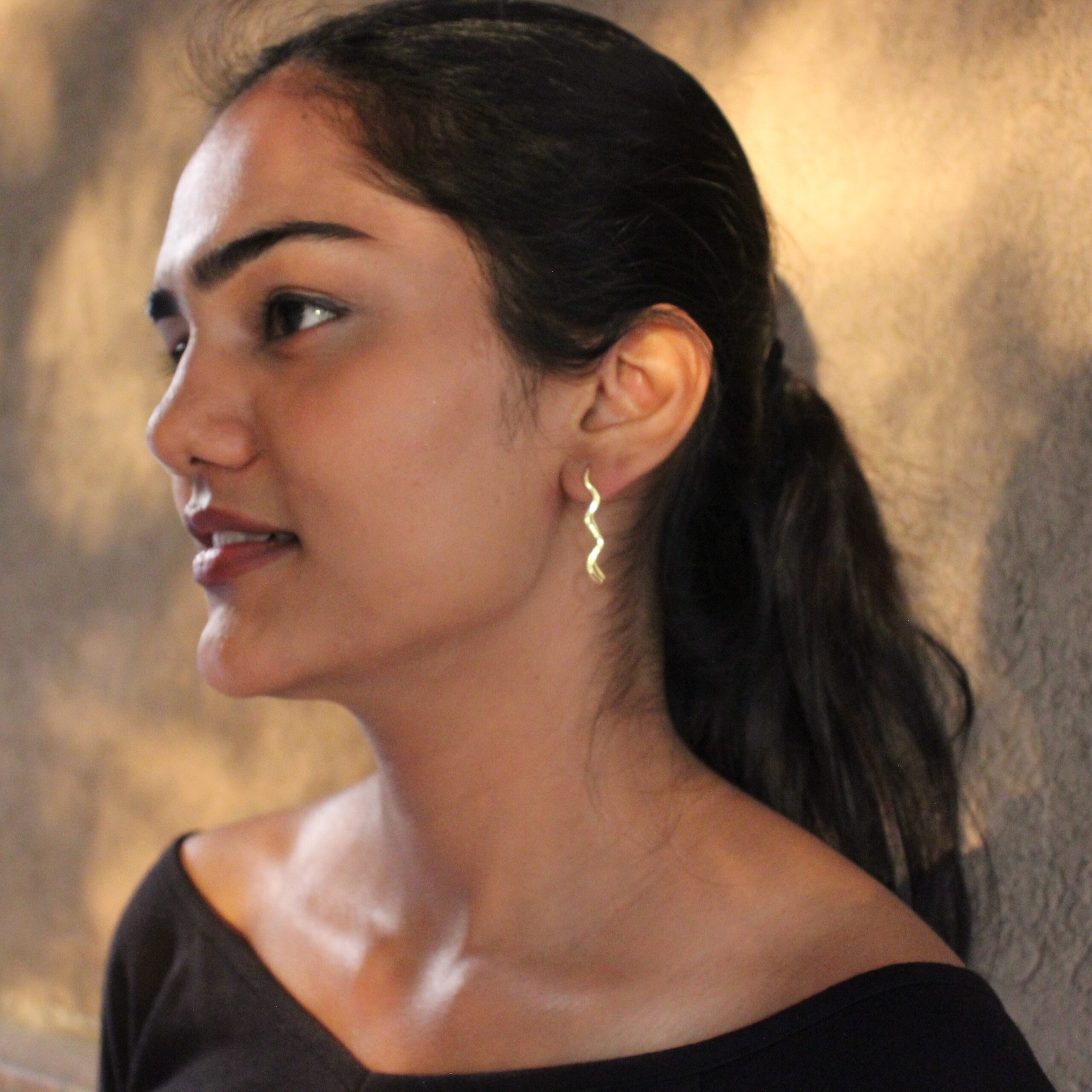 Close-up of gold-plated wavy earrings, modern sculptural jewelry design