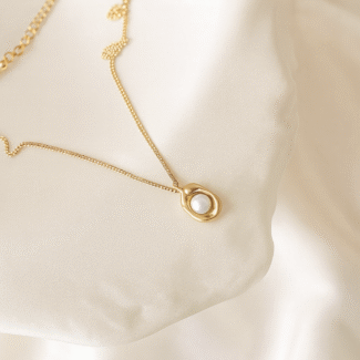 18 carat gold plated necklace with pearl pendant on satin background