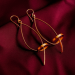 Unique geometric loop drop gold plated earrings with circular accents on maroon satin fabric