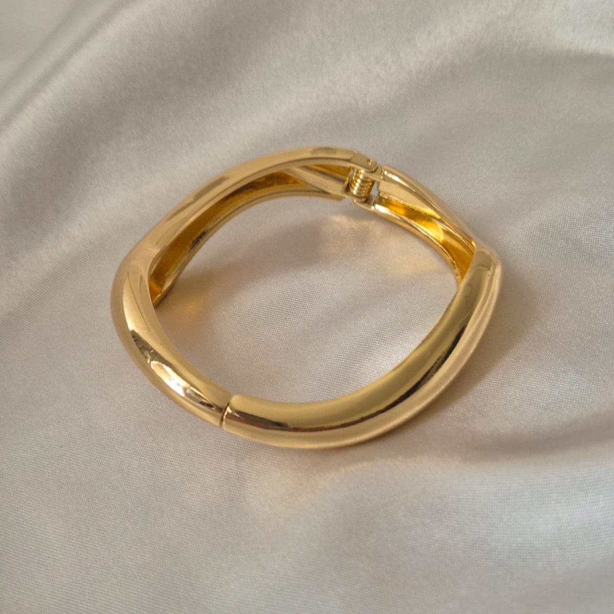 Nova Bold Hinge Bangle – 18 Carat Gold Plated Sculptural Bracelet by Masaira Polished gold-plated bold square bangle with hinge clasp on satin background by Masaira