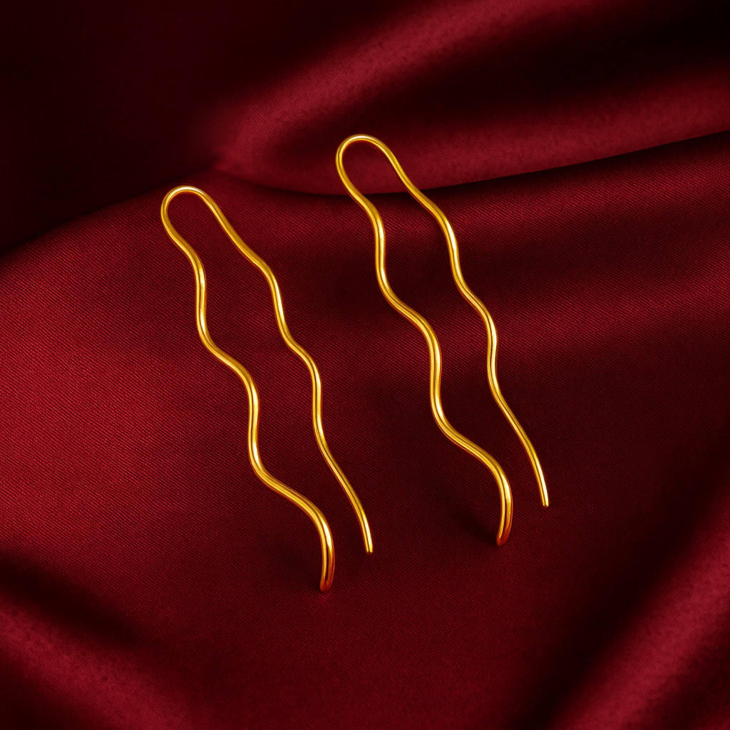 Minimalist wavy line gold plated earrings on maroon satin background