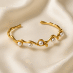 Pearl Wave Cuff in 18 carat gold plated stainless steel with sculpted wave design and pearl accents.