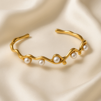 Pearl Wave Cuff in 18 carat gold plated stainless steel with sculpted wave design and pearl accents.